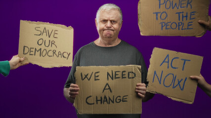 Man holding cardboard sign reading we need a change, shouting and gripping sign with both hands in...