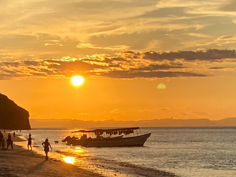 Balandra, Mexico. BCS. Golden sunset on a beach with fishing boat and people walking in the sand