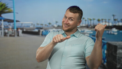 Man giving thumbs up toward anchored boats on a port pier street under clear blue sky  joy celebration leisure. © Krakenimages.com