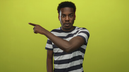 Young man pointing finger in studio wearing striped shirt with serious gaze; seriousness assertion intensity.