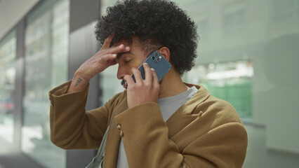 African american man multitasking on smartphone in urban city street, exhibiting a blend of focus...