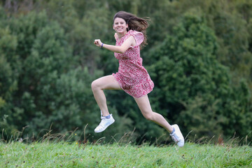 H&uuml;bsche Teenagerin h&uuml;pft und springt in der Natur