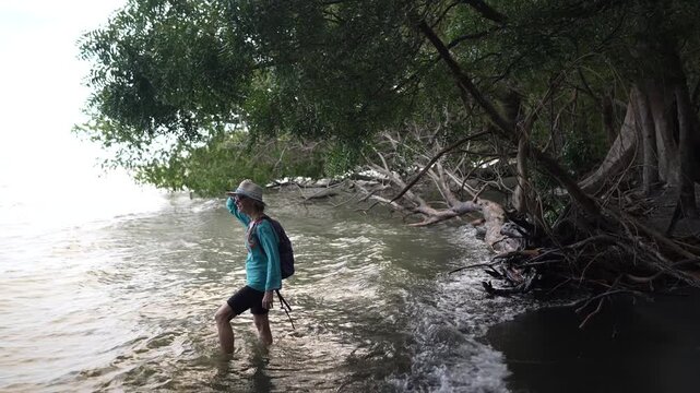 Mature woman hikes through Charco Verde park on Ometepe Island in Nicaragua, walking along the waters edge while enjoying nature.