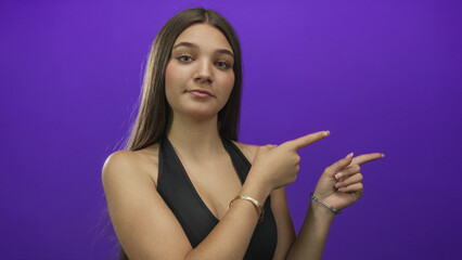 Obraz premium Caucasian teenage girl pointing finger at side with both hands in a clean full frame purple studio; boredom.