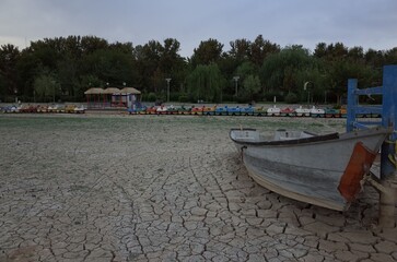 Dry lakebed with boat and colorful paddle boats