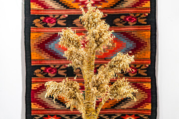 Vintage Christmas decorations on a colorful Native American blanket with geometric designs against a neutral background, featuring an abstract straw arrangement in the foreground Soft lighting enhan