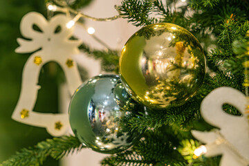 Indoor vintage Christmas scene with a decorated, angled view of an illuminated pine tree, featuring gold ornaments and a turned off string of lights Also visible is a possible gold bell ornament