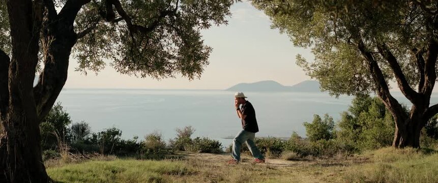 Vlora, Albania, 28 December 2025. A man practices shadowboxing during a solo outdoor workout near the sea. Static tripod shot captured with an anamorphic lens, surrounded by trees and coastal nature.