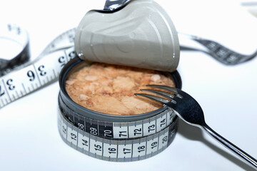 Healthy eating concept with open tuna can and measuring tape