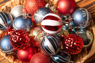Christmas balls, beautiful and colorful balls in a rustic basket on rustic wood, selective focus.