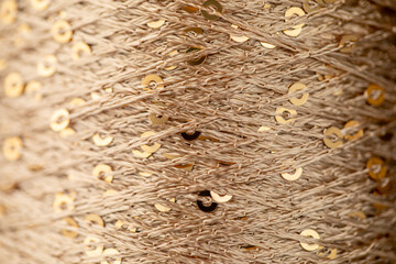 a skein of golden yarn with sequins for knitting in close-up, background for needlework