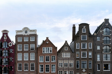 Naklejka premium Colorful Damrak canal waterfront houses, classic Dutch facades, famous travel destination. For tourist guides, travel blog visuals and social media posts