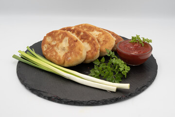 Homemade fried potato pies served with tomato sauce and fresh herbs on black slate plate