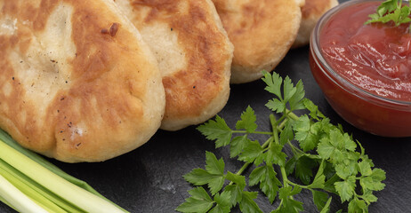 Homemade fried potato pies served with tomato sauce and fresh herbs on black slate plate