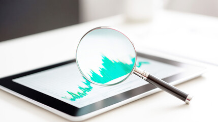 タブレットに表示された上昇する成長グラフと拡大鏡
