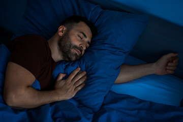 Calm man sleeping at home alone at night on comfortable bed in bedroom interior, top view. Sweet dreams concept © Home-stock