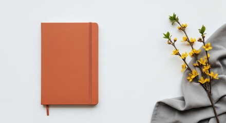 Orange notebook beside yellow blossoms