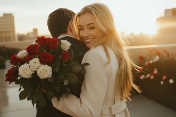 Happy woman embraces partner holding large bouquet of red and white roses during golden hour outdoors