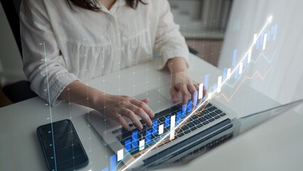 A woman engages with her laptop in a bright workspace while financial graphs overlay the scene. This image depicts the fusion of technology and business analysis, symbolizing growth. Copula