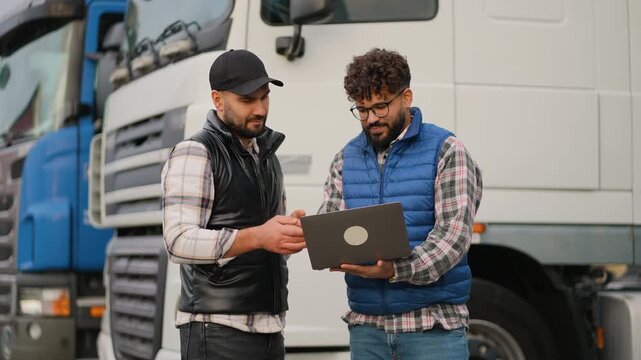Truck drivers discussing logistics and cargo shipment using a laptop