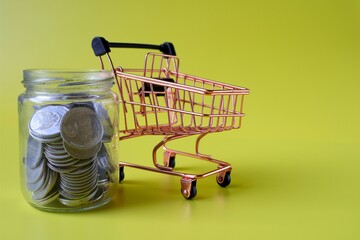 trolley and coins in a jar with a yellow background