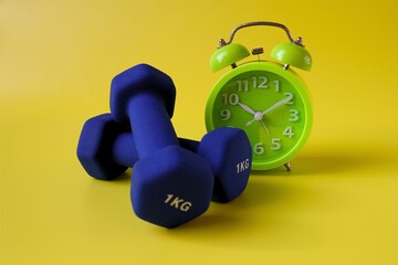 blue barbell and alarm clock on yellow background