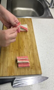 The process of peeling crab sticks, taking them out of the cellophane package in close-up