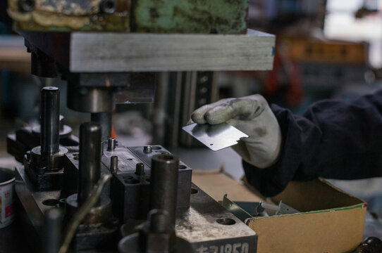 Precision metal stamping process with industrial press machine and worker handling aluminum part