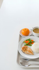 Hospital meal tray placed on the right side of a bright table, simple portions of balanced food, large clean white surface on the left serving as negative space for medical or nutrition messaging.