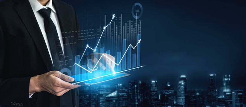 A businessman analyzes digital financial graphs on a tablet against a modern city skyline at night, showcasing concepts of growth, innovation, and technology. Scalp - Powered by Adobe