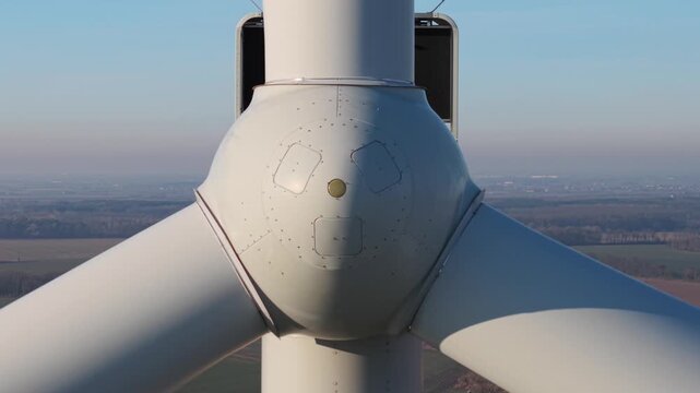 zoom out from close-up of a wind turbine against a clear sky, showcasing sustainable energy generation. view from the front
