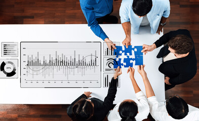 A diverse team collaborates to piece together a puzzle while surrounded by data charts and graphs, highlighting the importance of teamwork in a modern business environment. Trope