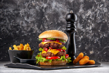 Tasty homemade sandwich and ketchup fries chicken nuggets on black board on gray distressed background