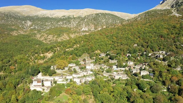 Aerial view of the traditional stone village of Papingo nestled in lush autumn forests at the foot of mountains in northern Greece.