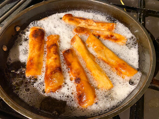 Spring rolls deep frying in a pan of hot oil	