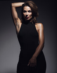 Striking editorial portrait featuring confident woman in fitted black halter dress with natural underarm hair, dramatic studio lighting, perfect for beauty campaigns and body positivity content