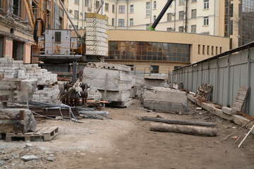 Workers are using equipment to manage building materials in the city. The site is busy and active