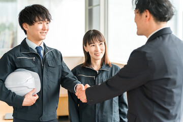 Male and female businessmen in work clothes shaking hands, workers