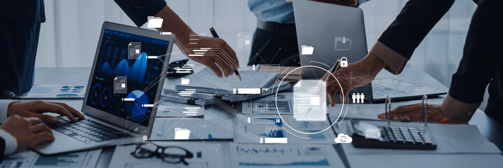 A dynamic business meeting showcasing hands working on laptops and documents, illustrating collaboration and technology integration in a modern office setting. Trope