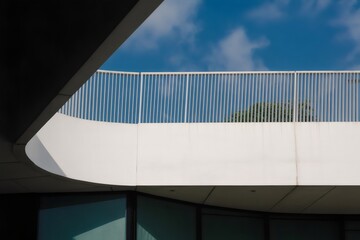 A modern building with a sleek white balcony and blue sky background
