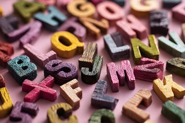 Many multicolored wooden letters on a pink background. toy letters. english alphabet. View from above. Flat lay. Copy space for text