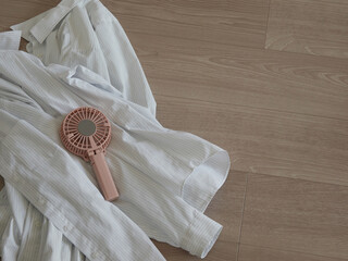 家のベランダの床にある夏用のシャツと携帯扇風機の様子