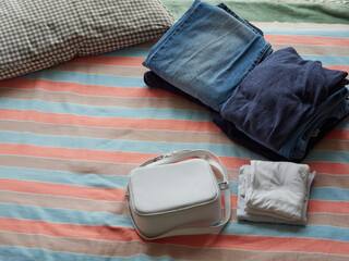 布団の上にある鞄と整理されたズボンと服