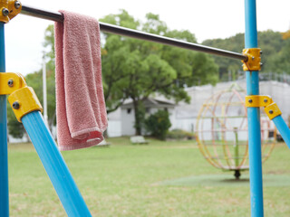 昼の公園の鉄棒に掛かってあるタオルの様子