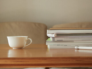 家のリビングの机の上にあるノートブックとコーヒーカップの様子