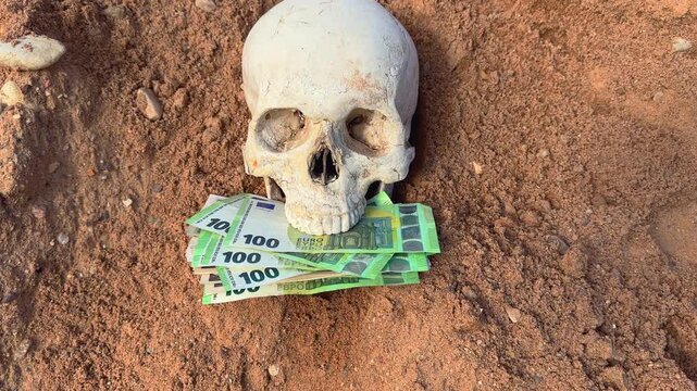Skull with EU money as death of wealth. Human skull with euro bills in its mouth lies on ground in grave. Skeleton with euro money. Skull with euro bills money on ground on sunset. EU Dead banknotes. 
