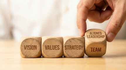 Wooden cubes representing leadership alignment being placed manually using macro clarity and soft white background blur