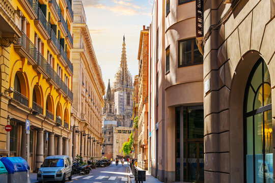 Sunlight hits the spire of the Gothic Barcelona Cathedral at from the narrow streets of the Gothic Quarter Barri G&ograve;tic district of Barcelona, Spain.