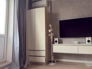 A living room features a television mounted on the wall with speakers and storage cabinets