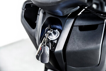 Close up of motorcycle ignition with inserted key and keychain on black body panel isolated on white background showing transport security control detail © Tatiana